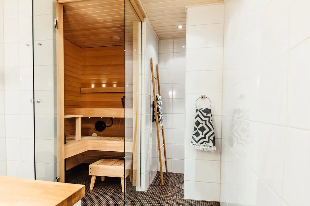 A white tile and wood luxury bathroom sauna